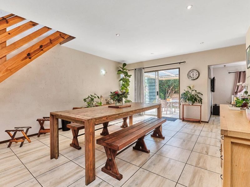 Open-plan dining area featuring tiled flooring, a wooden staircase, and direct access to the rear patio through sliding glass doors.
