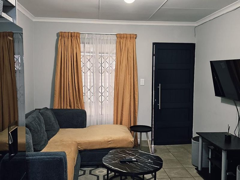 A functional living room featuring tiled flooring, a secure entrance door, and neutral wall finishes, providing a comfortable and practical living space.