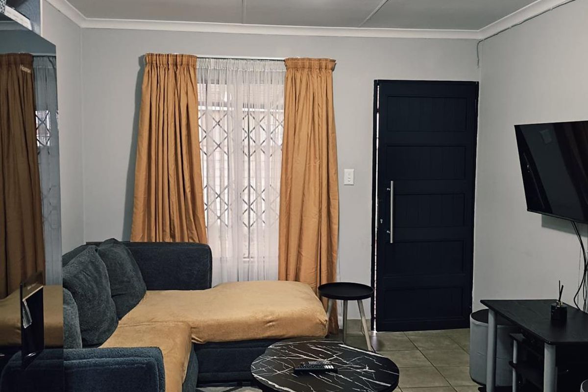 A functional living room featuring tiled flooring, a secure entrance door, and neutral wall finishes, providing a comfortable and practical living space.