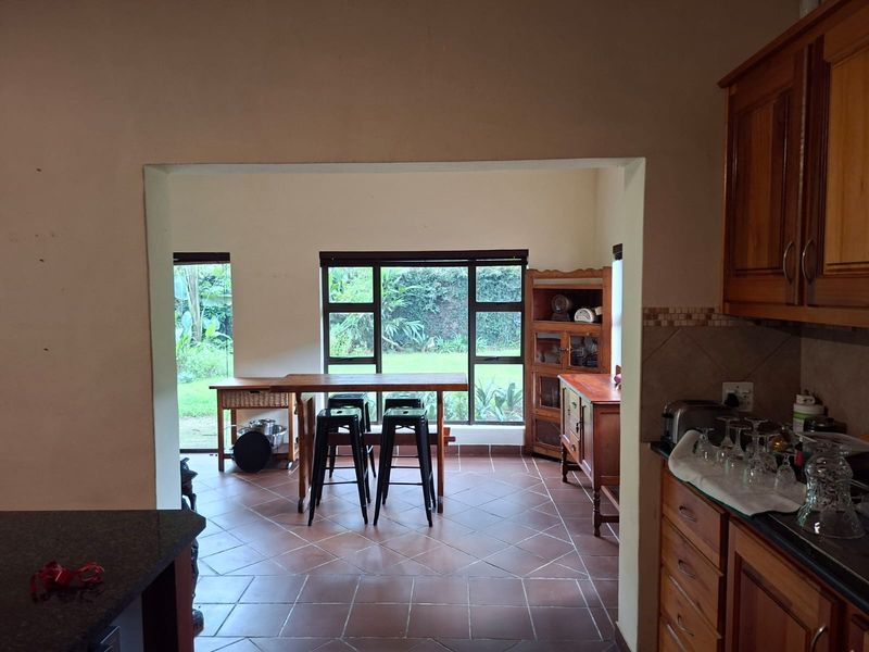 Open plan kitchen and dining area featuring wooden cabinetry, granite countertops, and large windows overlooking the garden.
