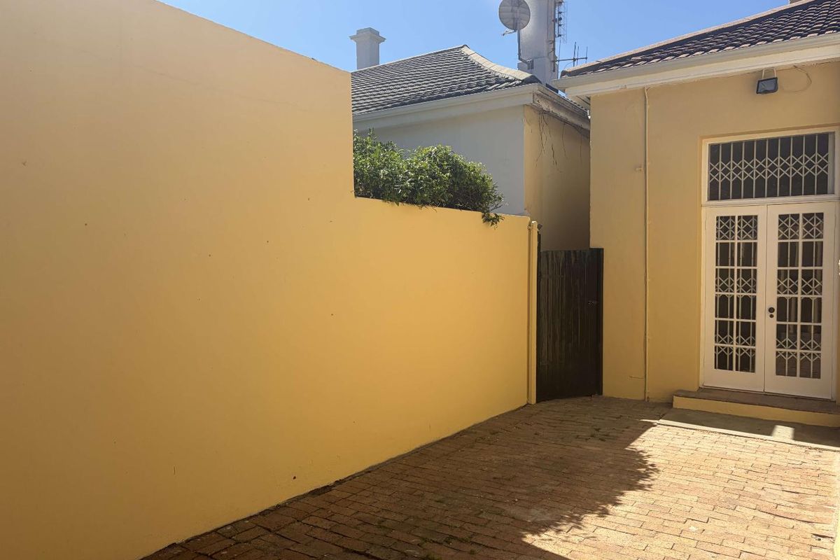 A private rear courtyard featuring brick paving, a high boundary wall, and secure french door access to the main dwelling.