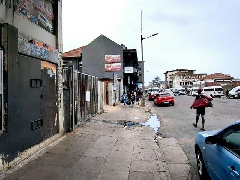 Street view showing the exterior facade of a commercial building with security gates and adjacent public pavement.