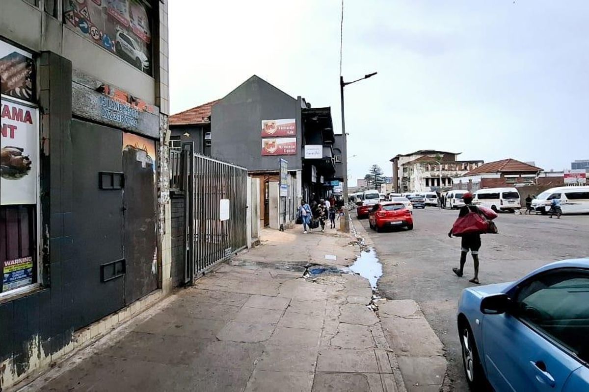 Street view showing the exterior facade of a commercial building with security gates and adjacent public pavement.