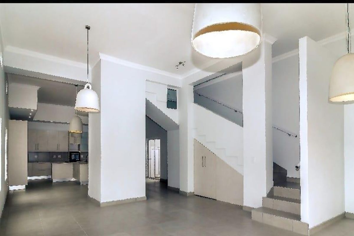 Spacious open-plan living area featuring tiled floors, a central staircase with under-stair storage, and a modern kitchen visible in the background.