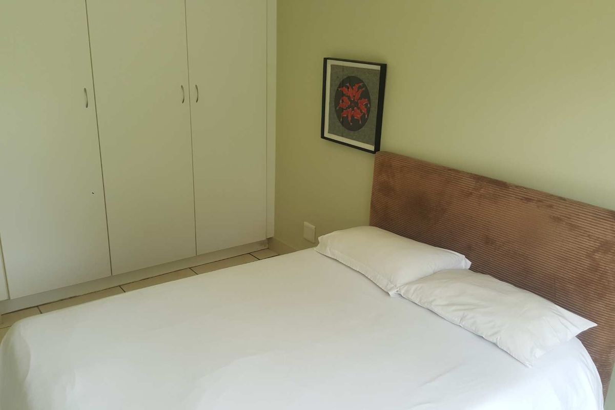 A bedroom featuring built-in wardrobes with white cabinetry and tiled flooring.