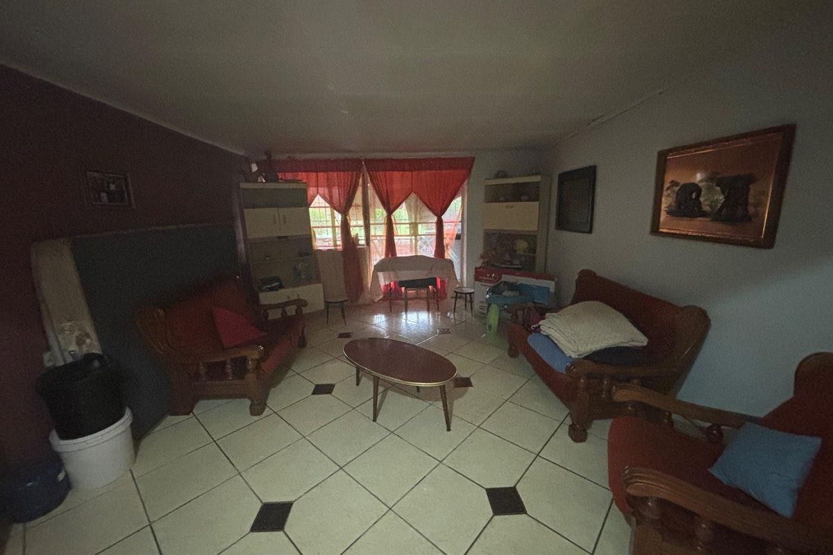 A living room area featuring tiled flooring with decorative inserts and access to an outdoor space through a doorway.