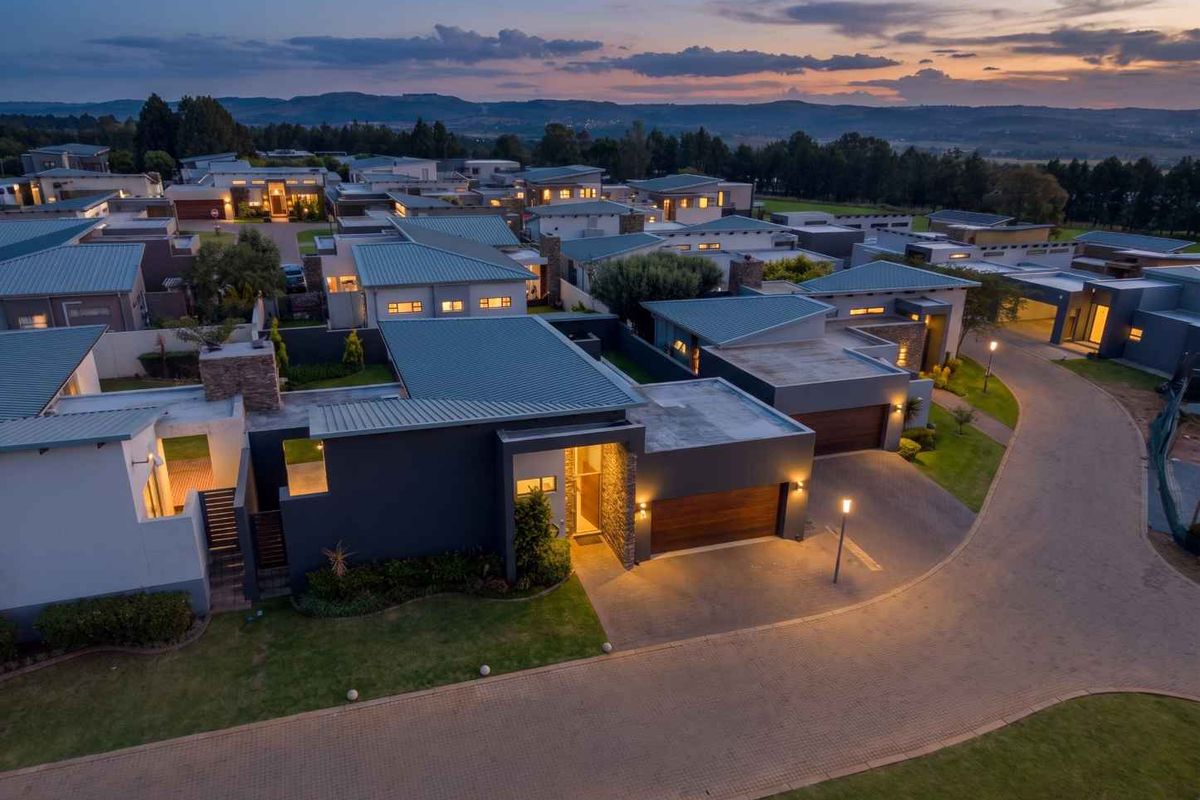 Aerial twilight view of a modern residential estate featuring contemporary homes with metal roofs, stone accents, and paved driveways.