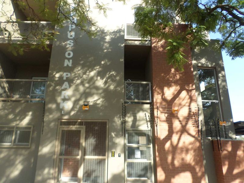 Front facade of Puson Park apartment complex featuring brick and rendered finishes, security gates, and electric fencing.