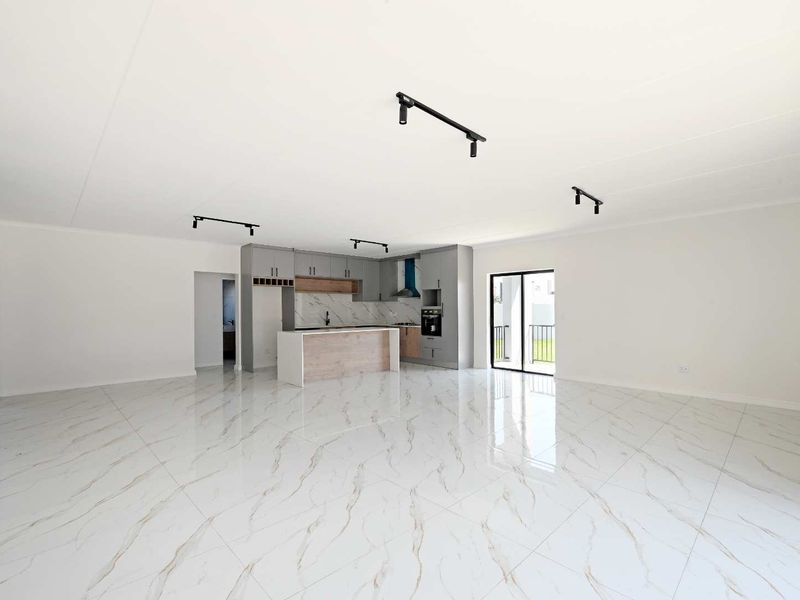 Spacious open-plan living area featuring high-gloss marble-look floor tiles, modern kitchen cabinetry with an island, and direct access to a balcony.