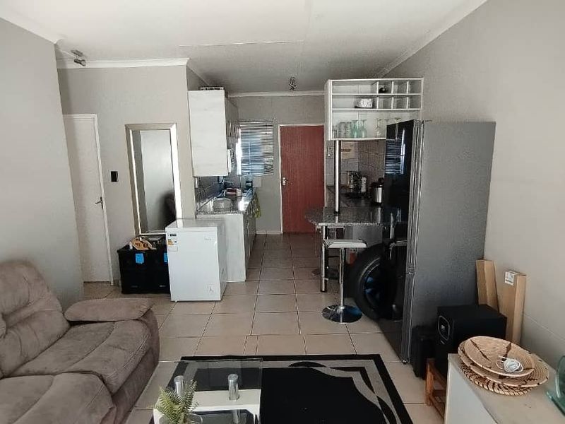 Open-plan living and kitchen area featuring tiled flooring, granite countertops, and a breakfast bar, creating a functional and connected living space.