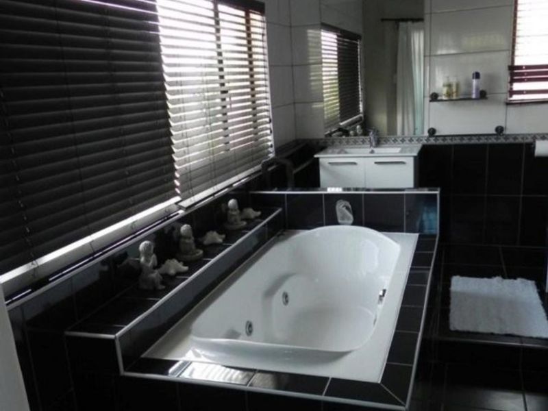 A bathroom featuring a built-in bathtub, vanity cabinet, and contrasting black and white wall and floor tiling.