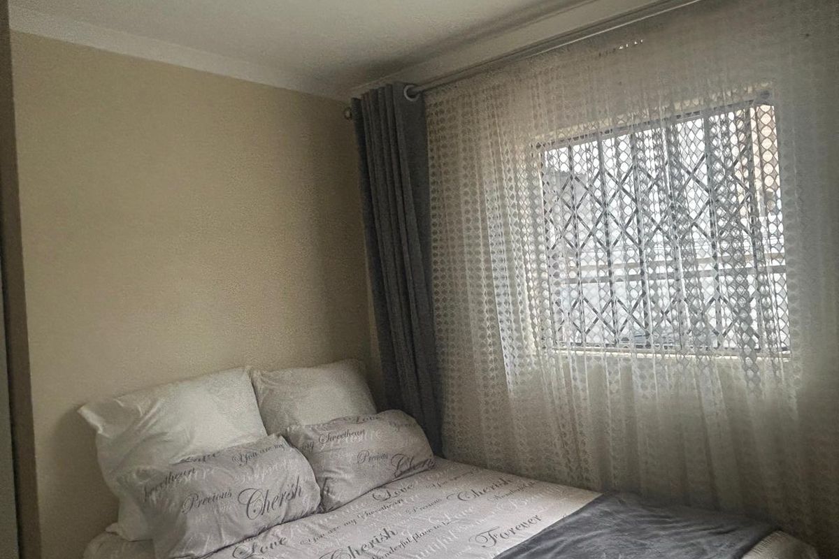 A cozy bedroom featuring a window with a security gate and neutral wall finishes.