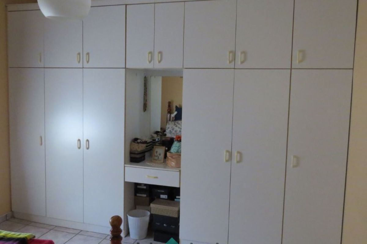 A bedroom featuring a large, floor-to-ceiling built-in wardrobe with integrated vanity and mirror.
