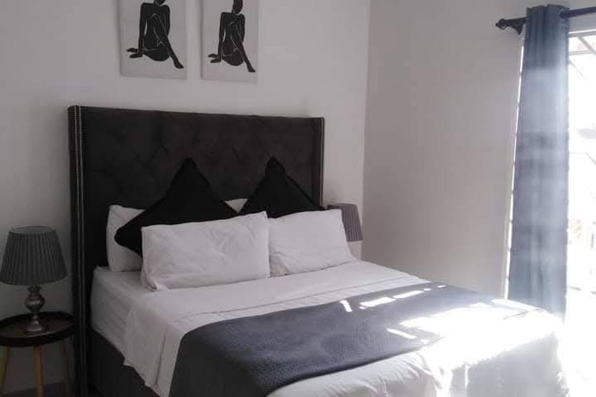 A well-maintained bedroom featuring neutral tiled flooring and a central ceiling light fixture, offering a clean and functional living space.
