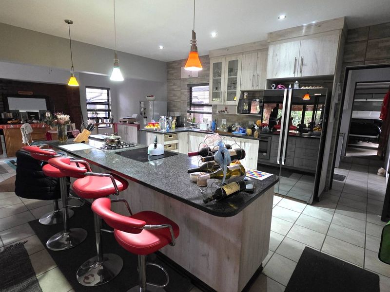 Spacious open-plan kitchen featuring a large granite island, modern cabinetry, stone feature wall, and integrated appliances, perfect for casual dining and entertaining.