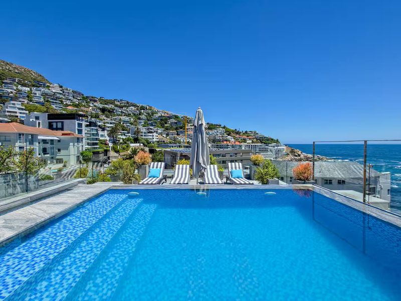 A stunning penthouse swimming pool featuring a glass balustrade, offering panoramic ocean and coastal views.