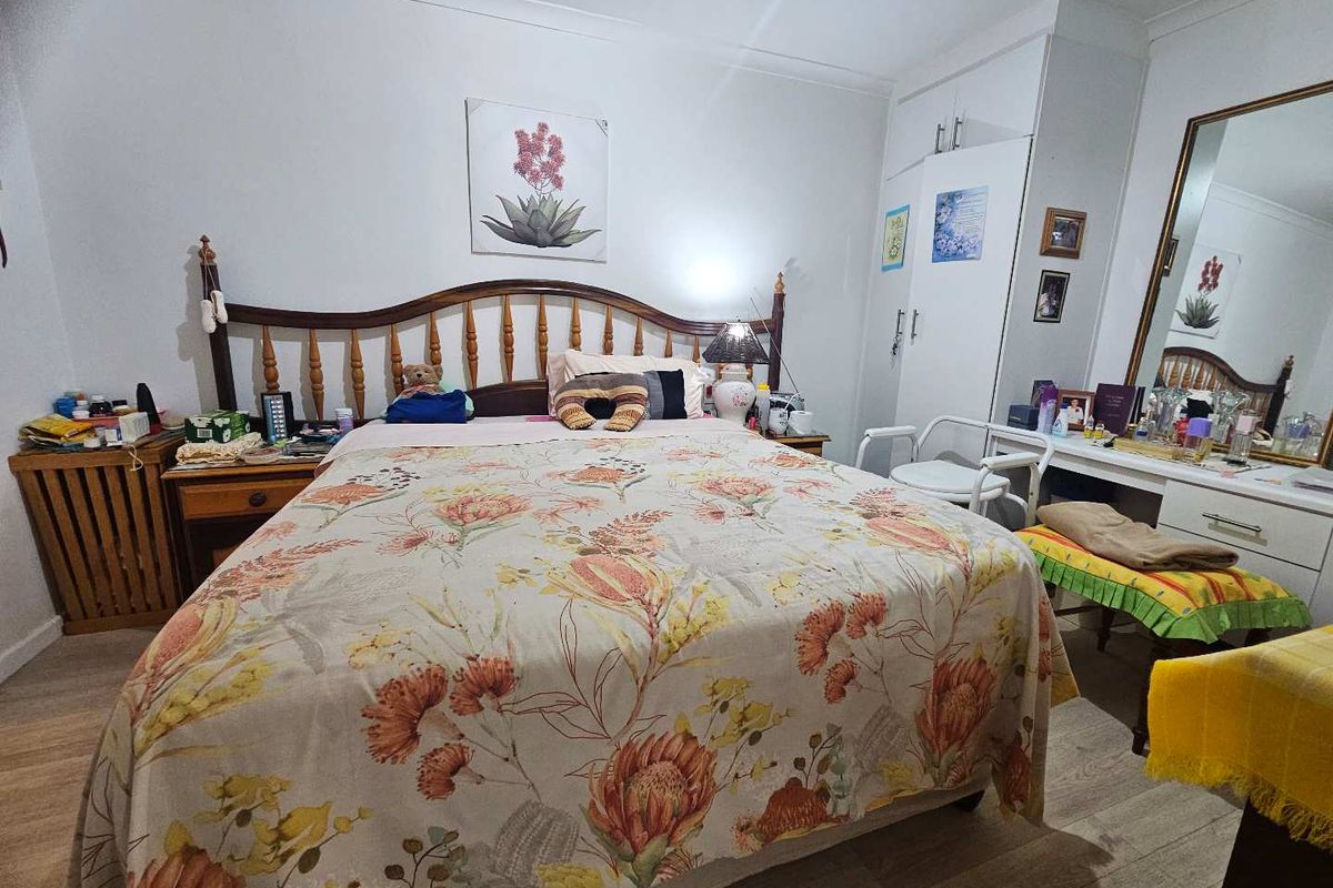A functional bedroom featuring built-in wardrobe storage, laminate flooring, and classic cove cornicing, offering a comfortable and practical living space.