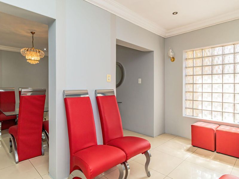 Open plan living area featuring tiled flooring, recessed lighting, and a distinctive glass block window, creating a bright and connected space.
