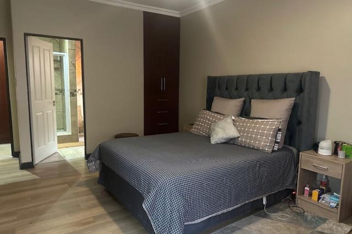 A well-maintained bedroom featuring built-in cabinetry, light wood-look flooring, and an en-suite bathroom entrance.
