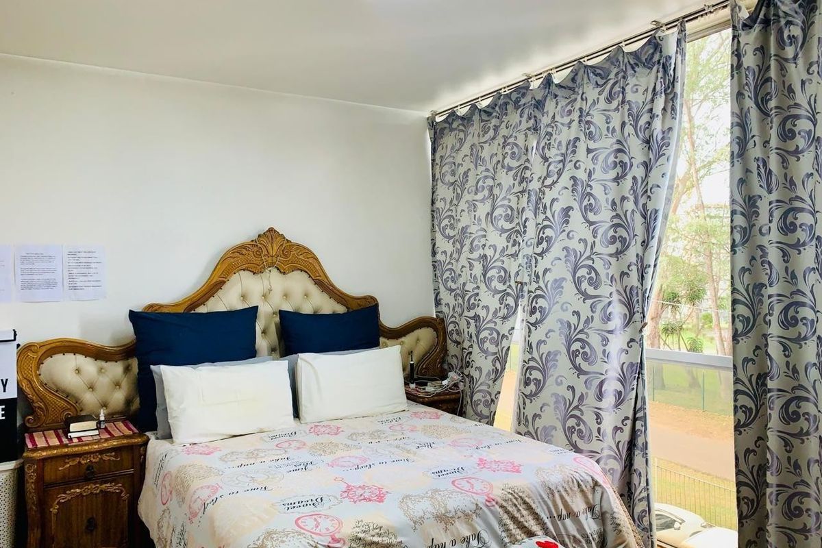A bedroom featuring a large window with natural light and neutral wall finishes.