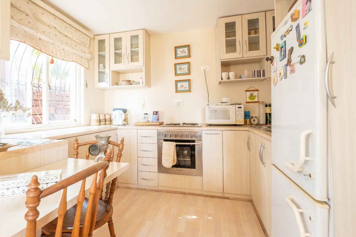 A functional kitchen featuring light wood cabinetry, built-in oven, hob, and ample counter space with a window providing natural light.