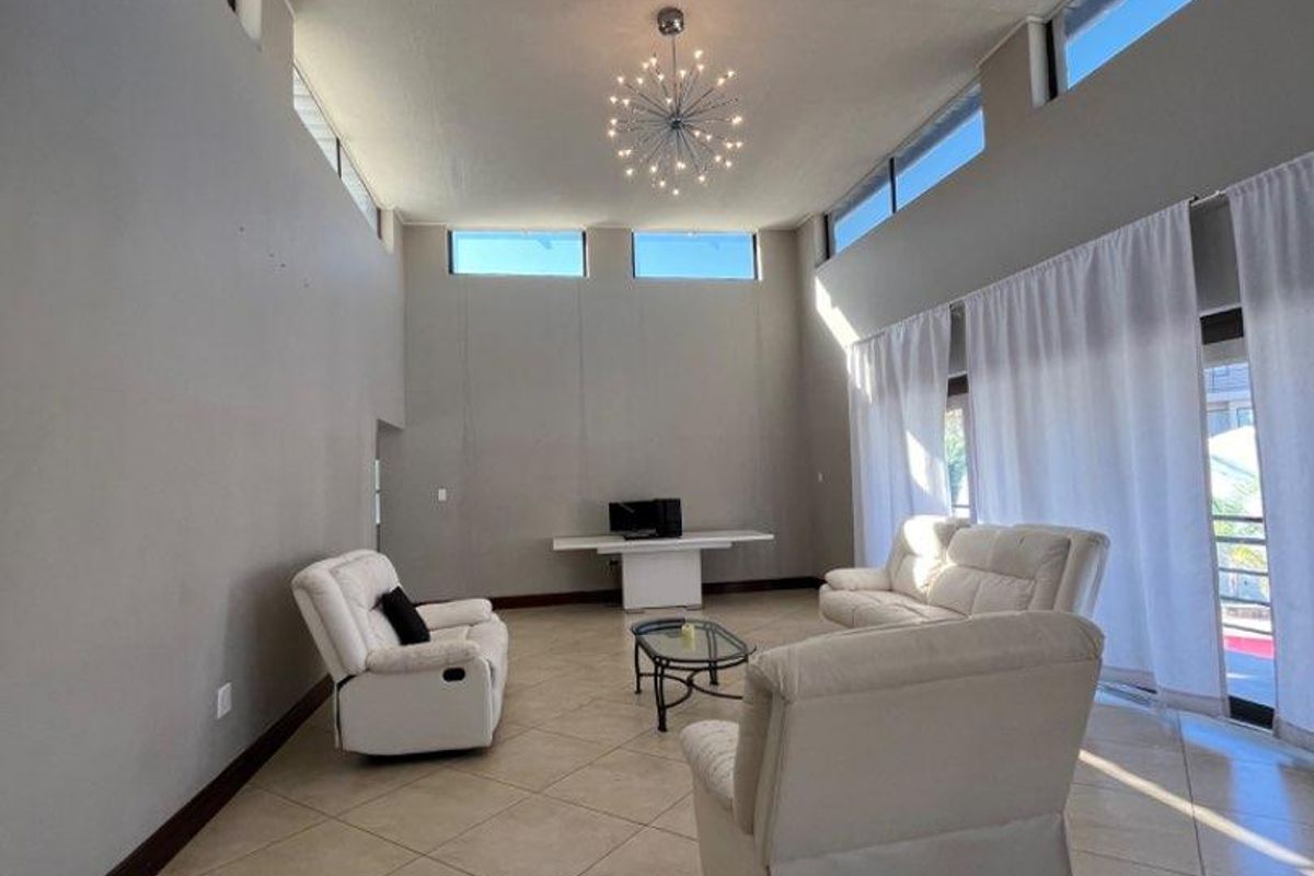 Spacious living room featuring high vaulted ceilings, clerestory windows for natural light, and large sliding glass doors leading to an outdoor area.