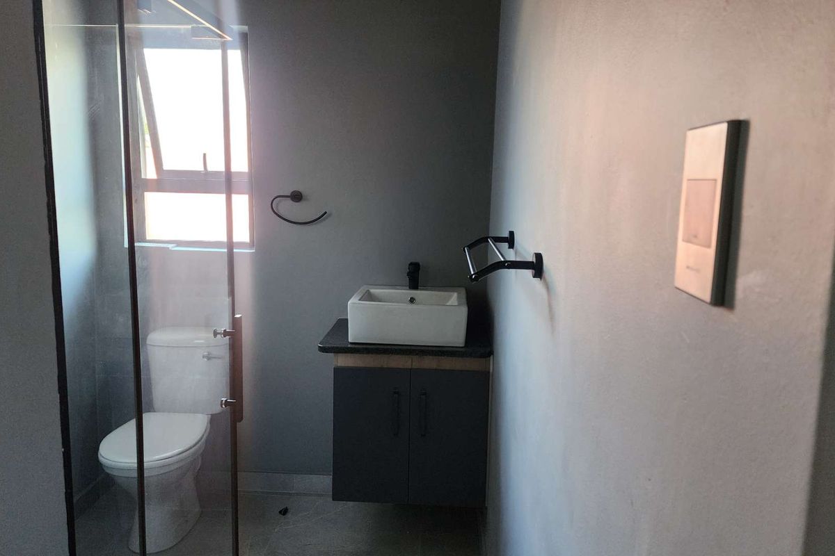 Modern bathroom featuring a floating vanity with a vessel sink, glass-enclosed shower, and contemporary matte black fixtures.