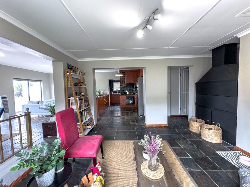 Open plan living area featuring slate tile flooring, a built-in fireplace, and a connected kitchen with wooden cabinetry and integrated appliances.