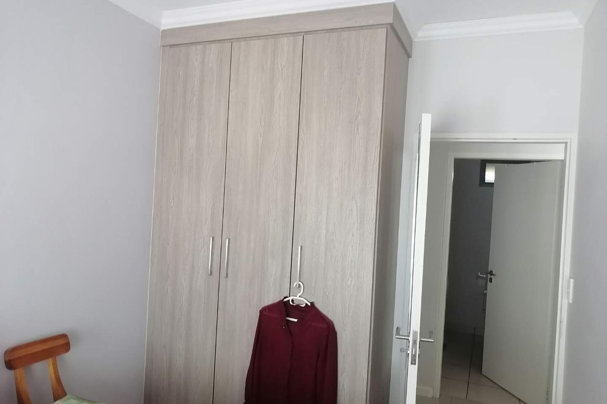 A bedroom featuring built-in wooden cabinetry with a modern finish and crown molding, providing ample storage space.