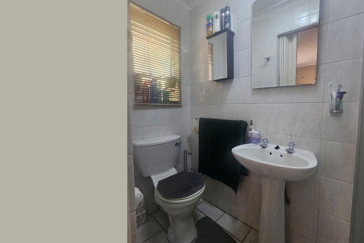 A functional bathroom featuring a pedestal basin, toilet, and tiled finishes, offering a clean and practical layout.