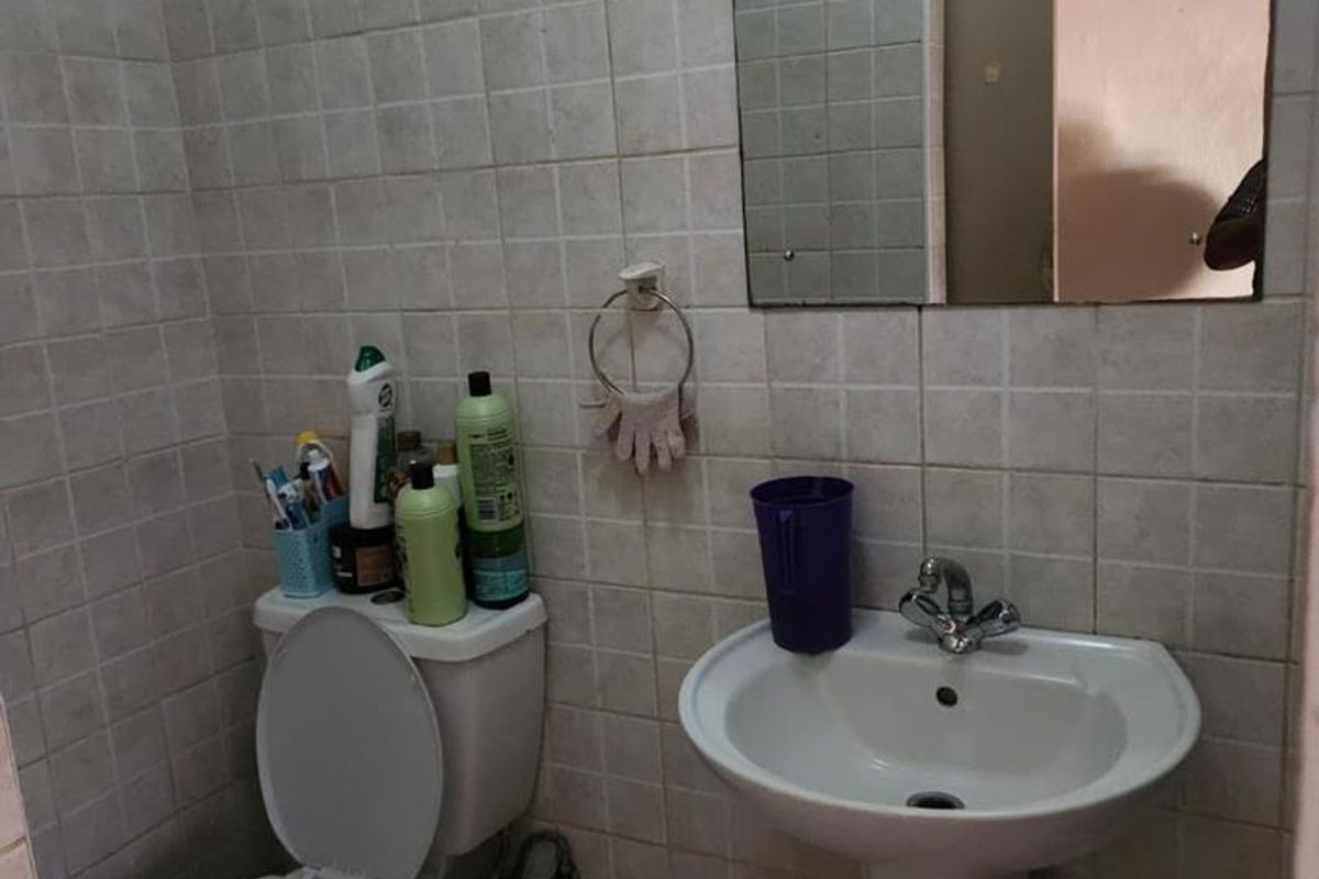Compact bathroom featuring a pedestal basin, toilet, and wall-mounted mirror, finished with full-height ceramic wall tiling.