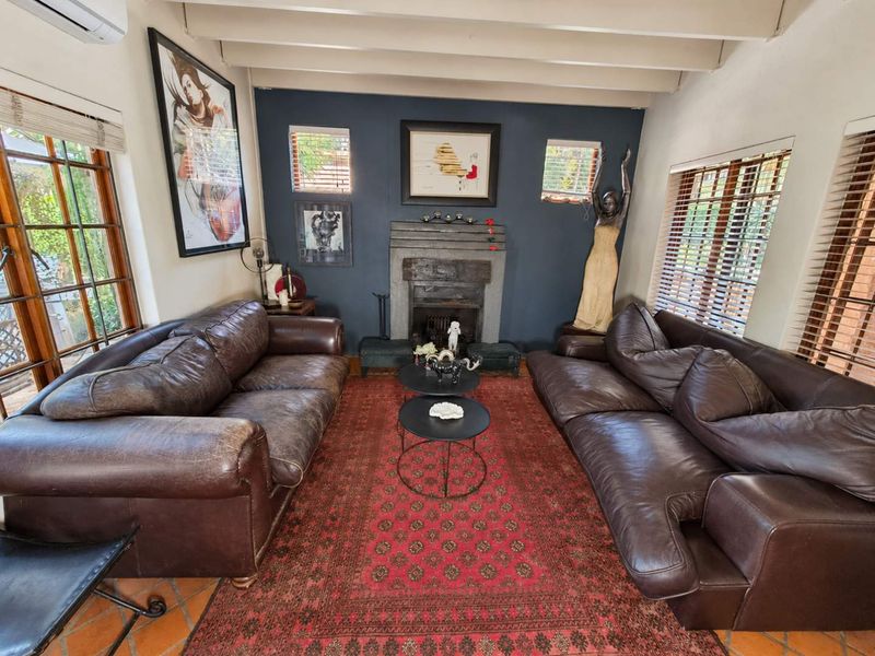 A cozy living room featuring a prominent fireplace, exposed ceiling beams, and traditional terracotta floor tiles, creating a warm and inviting atmosphere.