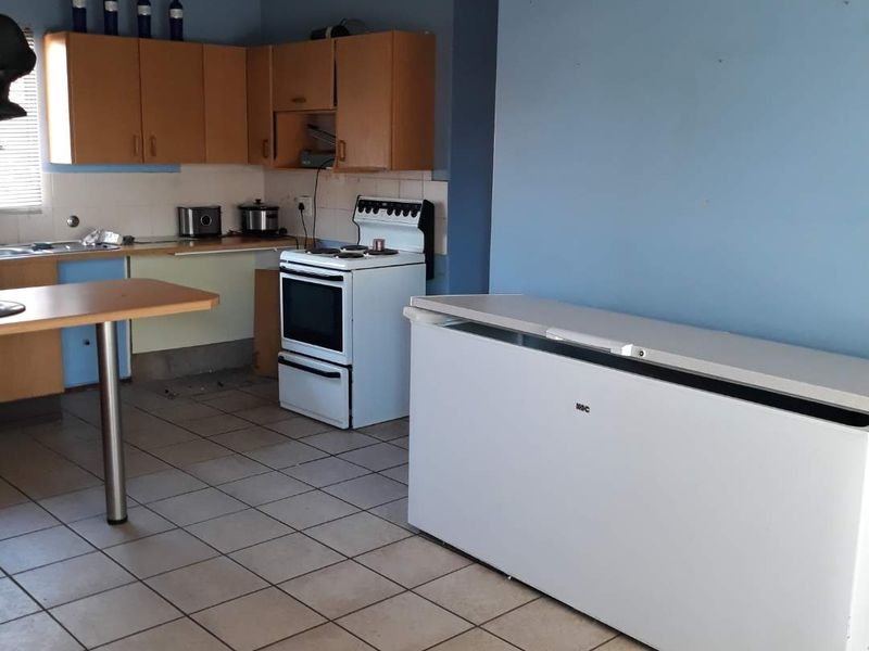 A dated kitchen featuring wood-tone cabinetry, tiled flooring, and a freestanding stove, offering significant potential for a modern renovation and aesthetic update.