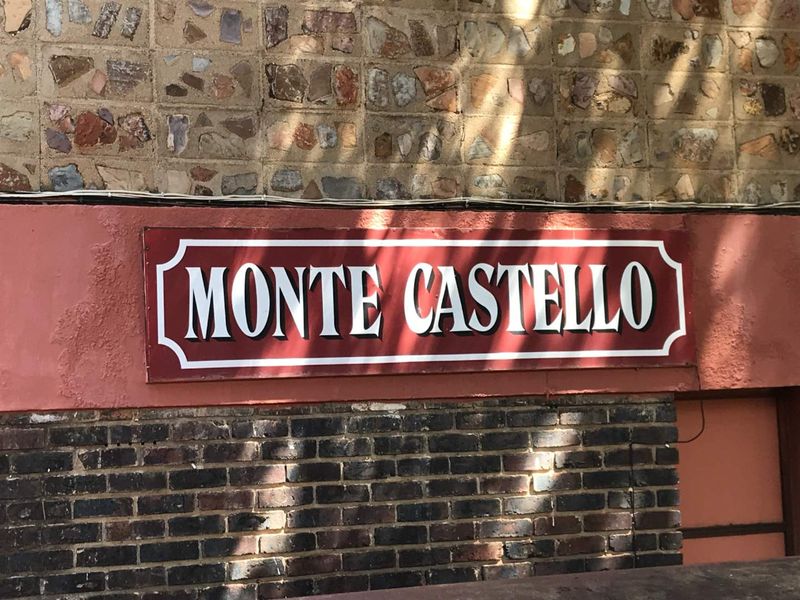 Exterior view of the Monte Castello building facade featuring stone and brick masonry with prominent complex signage.
