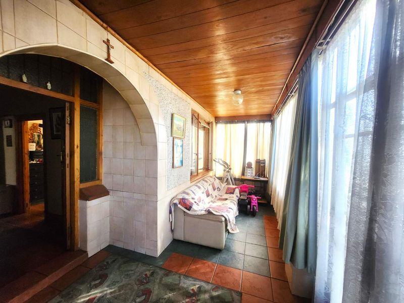 Enclosed patio area featuring a timber ceiling, tiled archway, and large windows providing ample natural light.