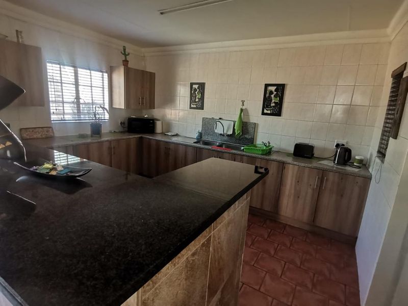 Functional kitchen featuring granite countertops, ample laminate cabinetry, a breakfast bar, and tiled flooring with a neutral backsplash.