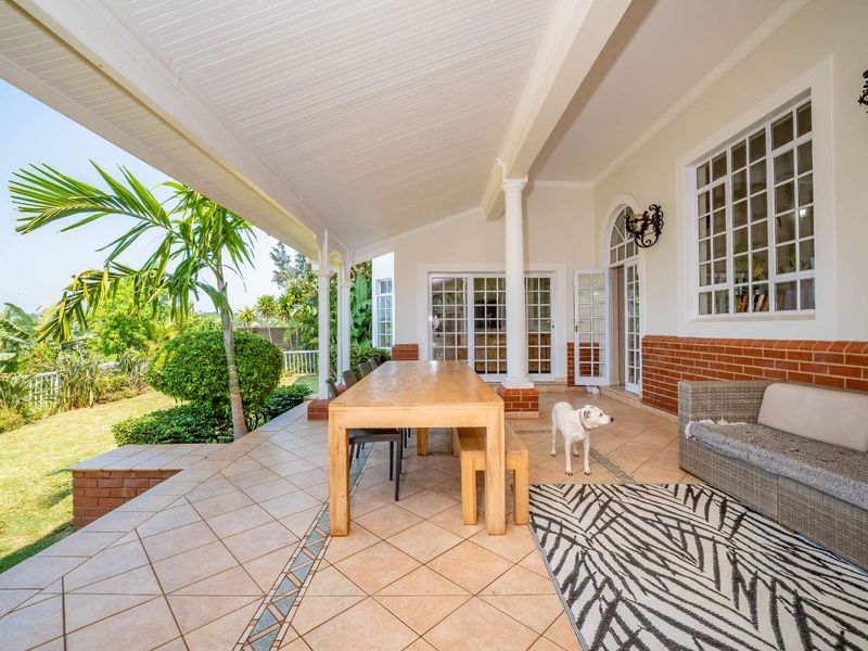 Spacious covered patio featuring tiled flooring, brick accents, and direct access to the garden through multiple sets of french doors.