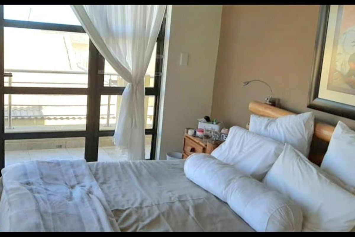 A bright bedroom featuring large floor-to-ceiling windows with access to a private balcony, providing ample natural light and a spacious feel.