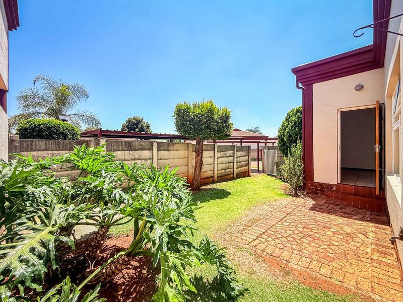 A private rear garden featuring a brick-paved patio area, established landscaping, and a secure precast concrete boundary wall.