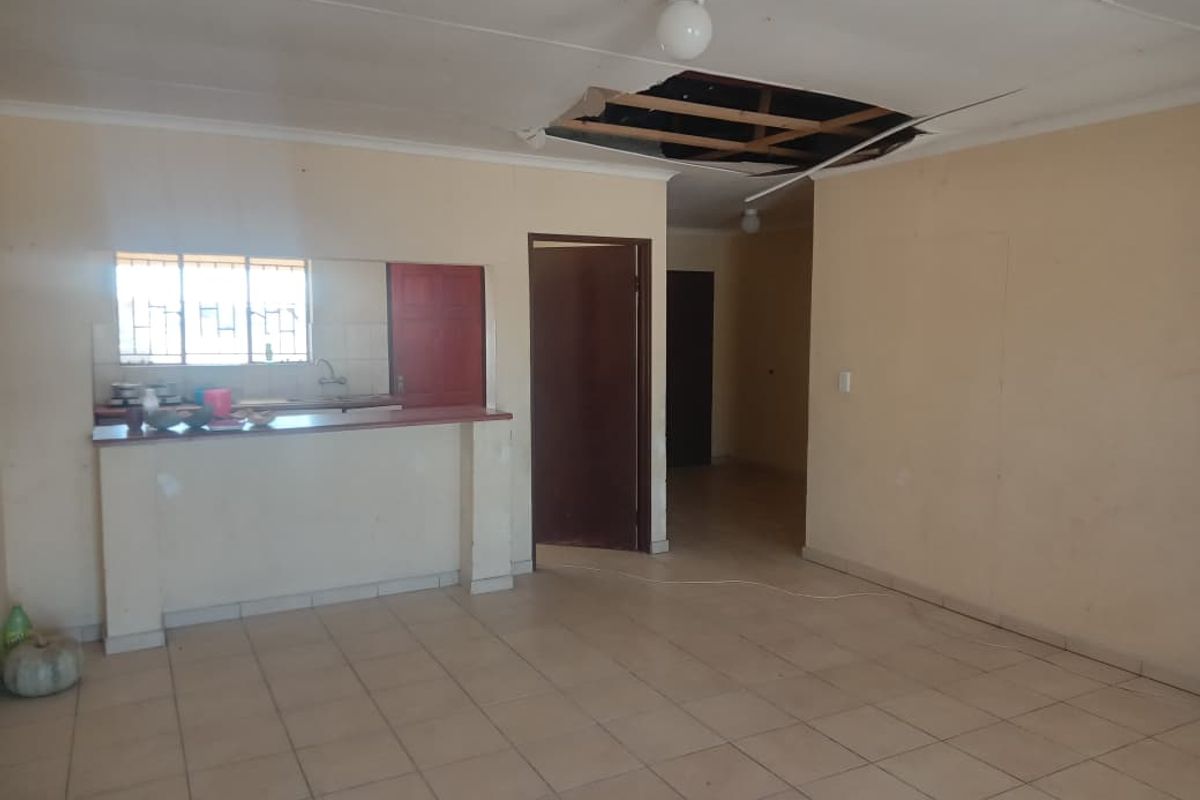 Open plan living area featuring tiled flooring and a breakfast bar, currently requiring ceiling repairs.