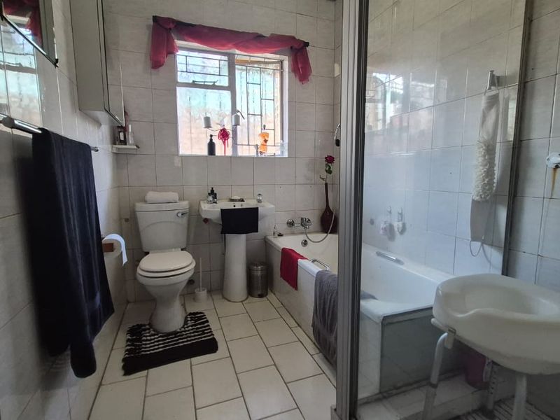 A functional bathroom featuring a pedestal basin, toilet, bathtub, and a separate shower enclosure with full-height wall tiling.