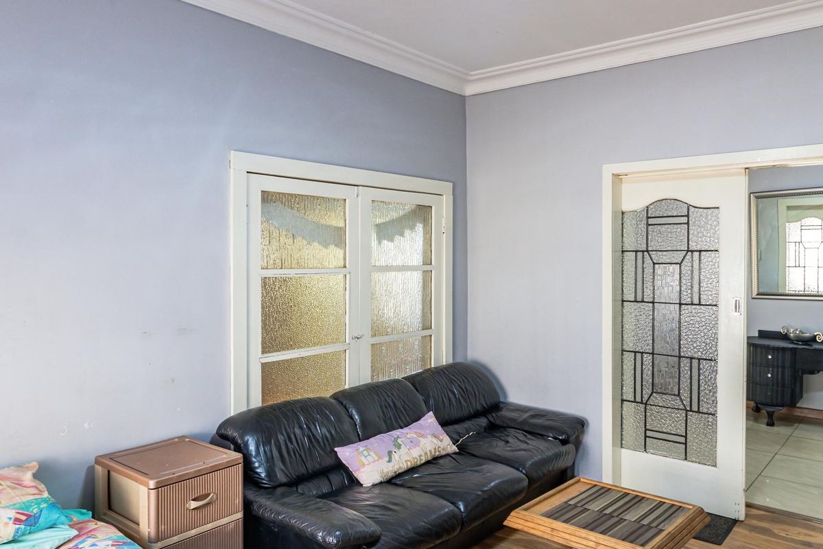 A living room featuring decorative glass-paneled double doors and a leadlight-style internal door, providing character and natural light flow between spaces.