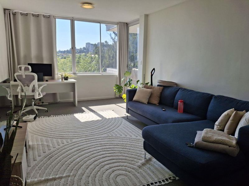 A bright and spacious living room featuring large windows that provide ample natural light and pleasant views.