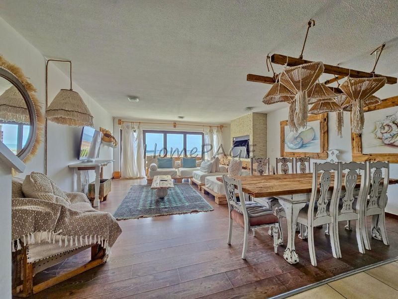 Spacious open-plan living and dining area featuring laminate flooring, a stone-surround fireplace, and large sliding glass doors with natural light.
