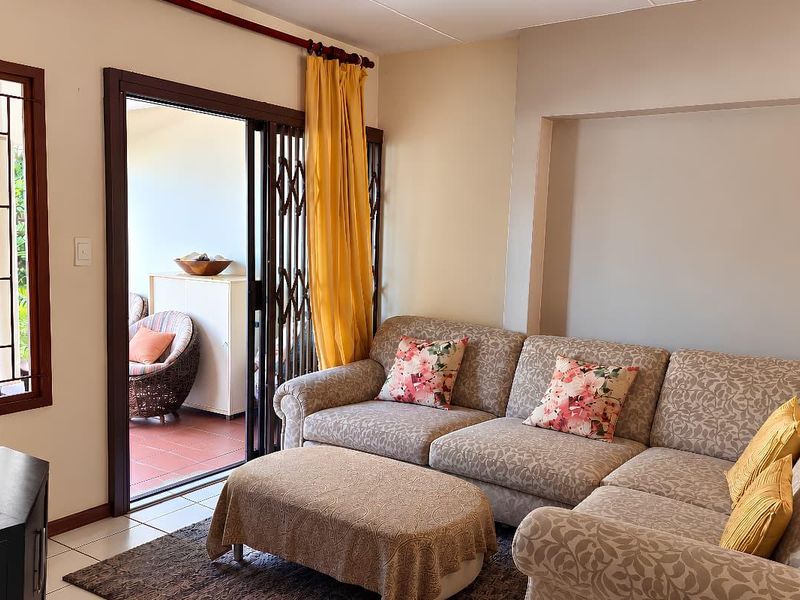 A comfortable living room featuring tiled floors, a recessed wall niche, and a sliding glass door providing access to an outdoor patio area.