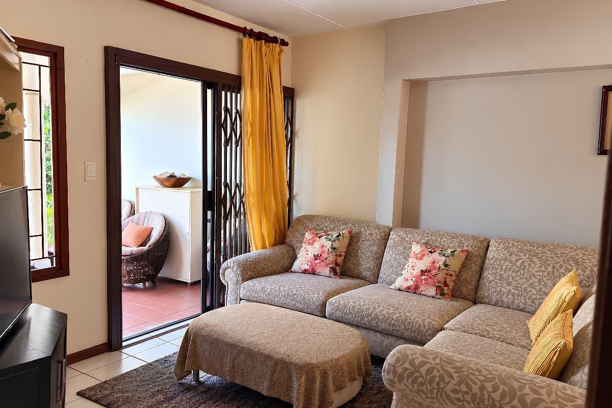 A comfortable living room featuring tiled floors, a recessed wall niche, and a sliding glass door providing access to an outdoor patio area.