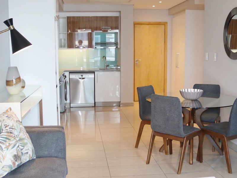Open-plan living and dining area featuring a modern kitchen with integrated cabinetry, sleek tiled flooring, and recessed lighting throughout.