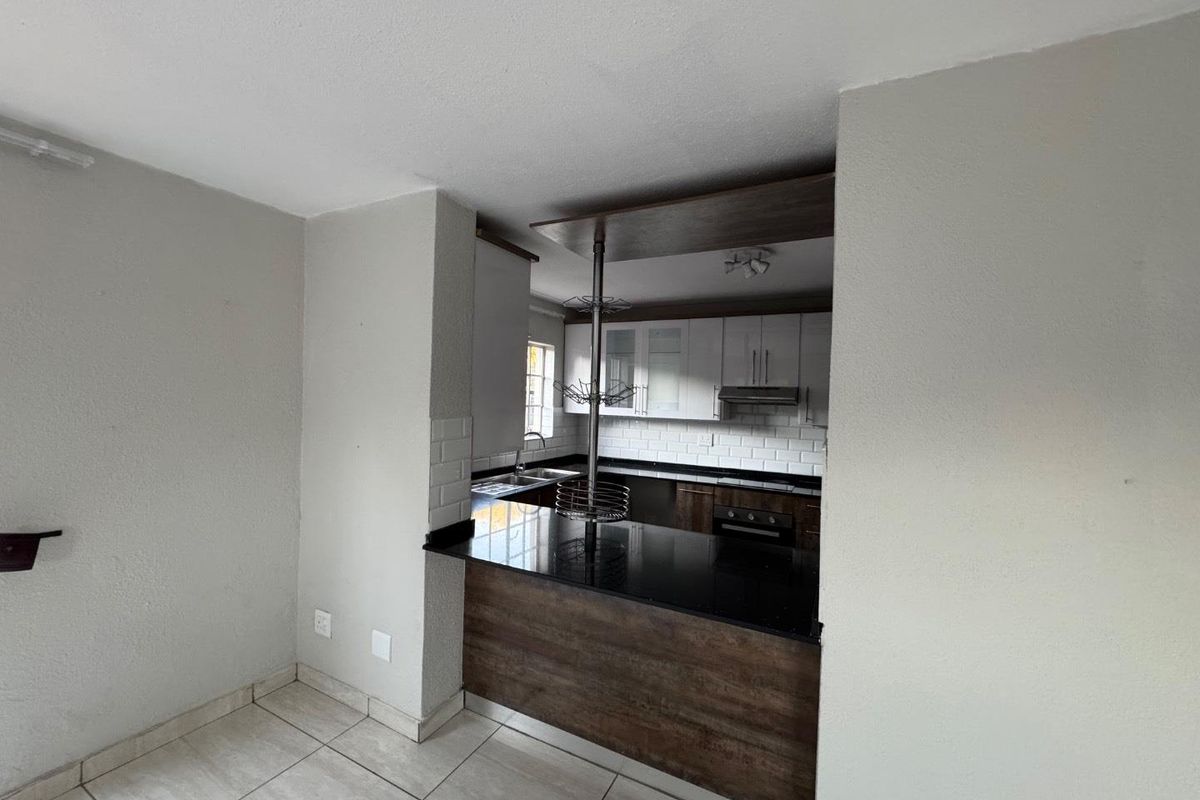 A functional kitchen featuring dark granite countertops, wood-look cabinetry, white subway tile backsplash, and a breakfast bar counter.