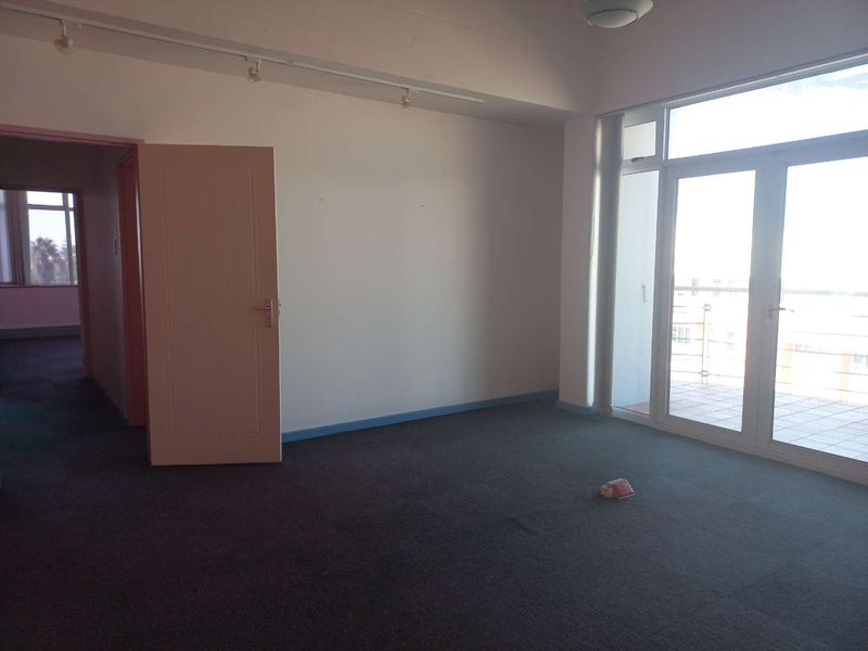 An empty office space featuring carpet flooring, track lighting, and direct access to an outdoor balcony area.