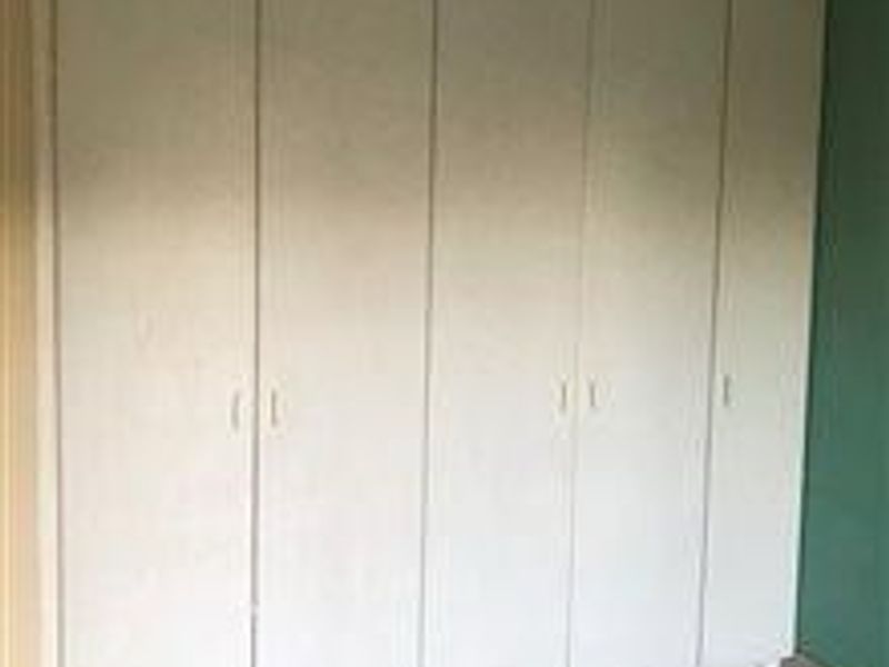A bedroom featuring floor-to-ceiling built-in cupboards with white doors.
